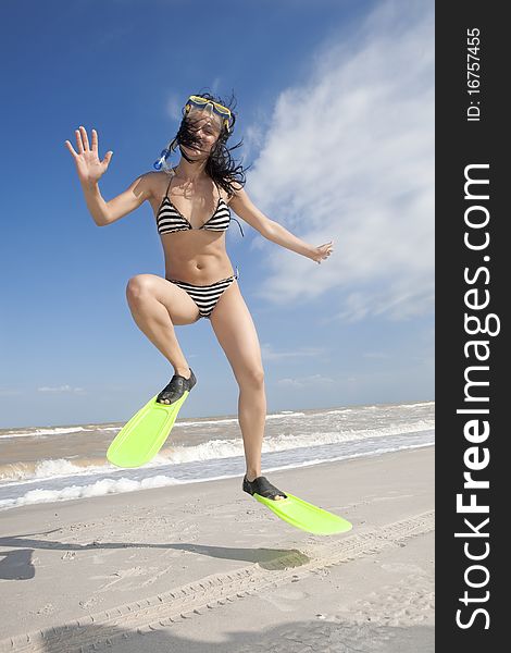 Girl in swimming mask and fins jumping at a beach