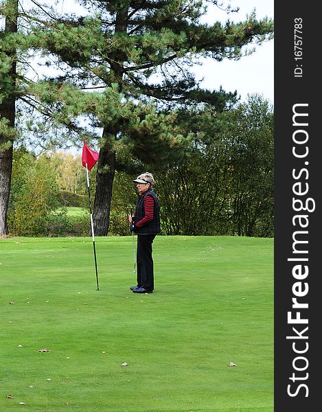 Female golfer standing next to putting flag