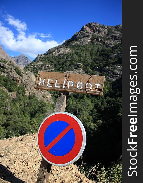 A heliport- and no-parking sign stands in the middle of nowhere between Corsica mountains, with no obvious helipad in sight. A heliport- and no-parking sign stands in the middle of nowhere between Corsica mountains, with no obvious helipad in sight.