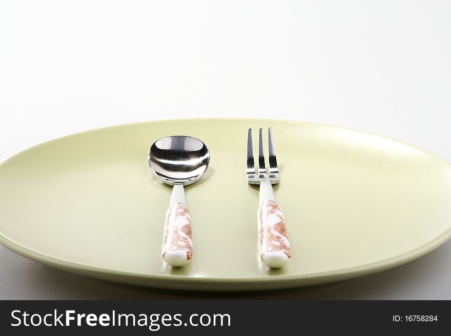 Fork and spoon on green plate