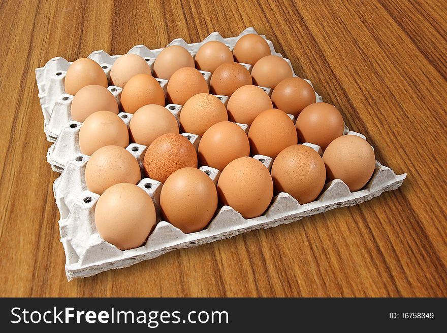 Carton of fresh brown eggs on Wood background