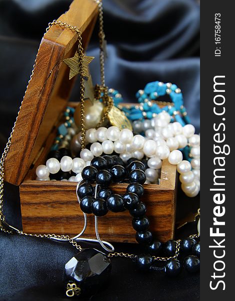 Jewelry pearls in a wooden chest on a black background