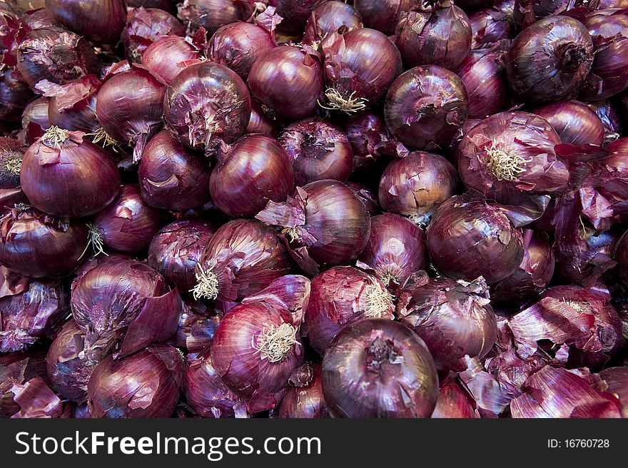 Red onions in a plile at a farm stand