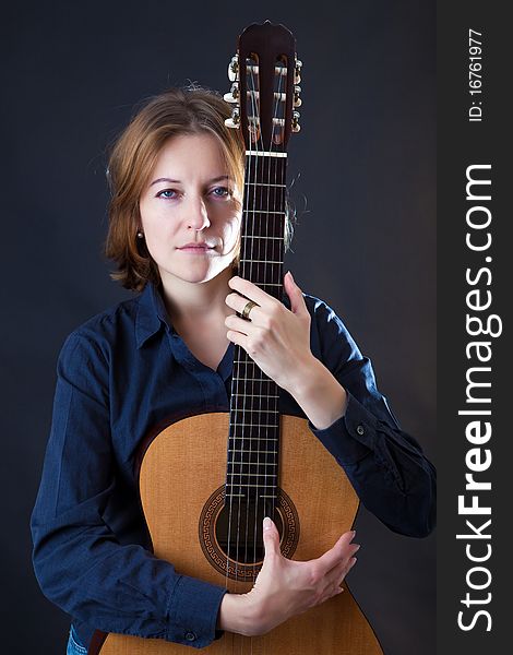Portrait of the girl with a guitar on a black background
