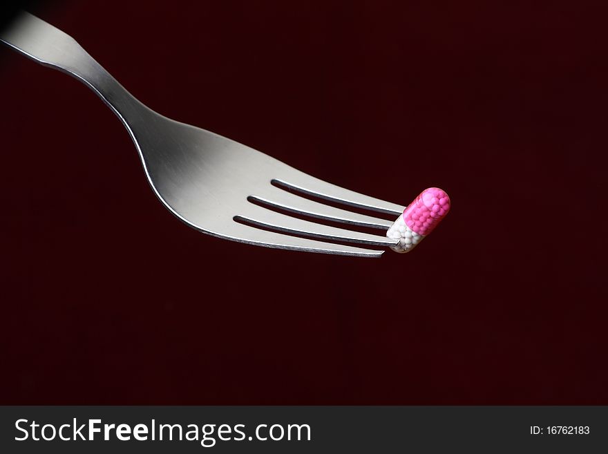 Conceptual shot of a capsule on a fork in a dark background