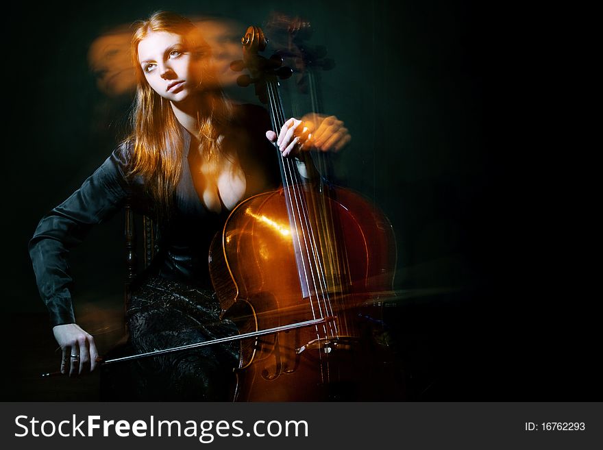 Young girl plays a violoncello against a dark blue smoke. Young girl plays a violoncello against a dark blue smoke