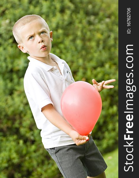 Young six year old boy holding a red balloon. Young six year old boy holding a red balloon