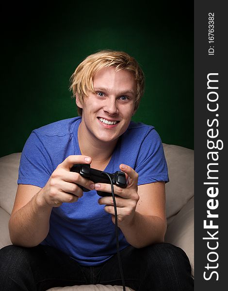 Young man playing video games over dark green background. Young man playing video games over dark green background