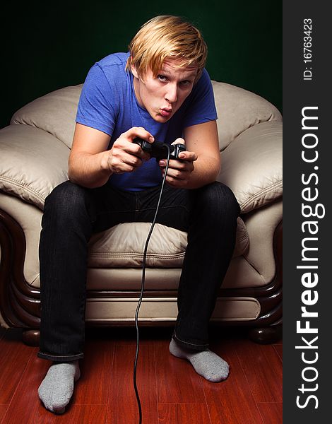 Young man playing video games over dark green background