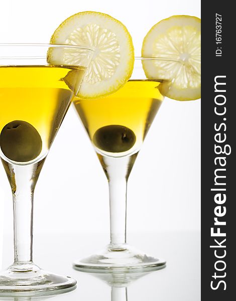 Two glasses with classical martini, garnished olive and lemon. Two glasses with classical martini, garnished olive and lemon.