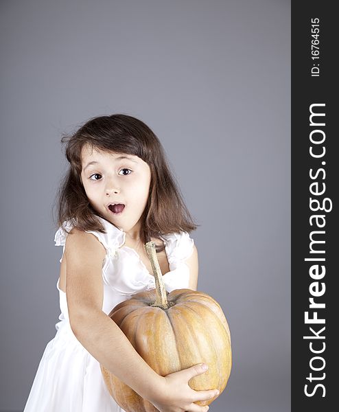 Young girl in dress with pumpkin. Studio shot.