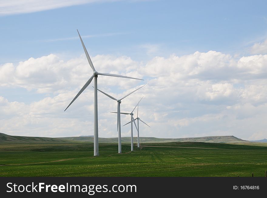 A row of wind turbines in a green grass field in the alberta prairies, canada. A row of wind turbines in a green grass field in the alberta prairies, canada