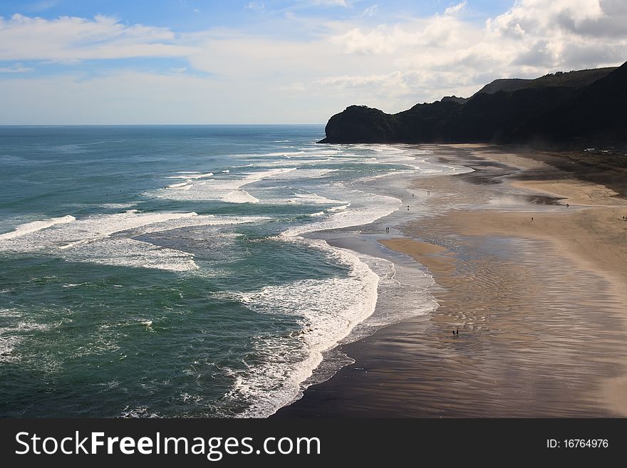 People walking on Beach with surf waves rolling in, piha, new zealand. People walking on Beach with surf waves rolling in, piha, new zealand