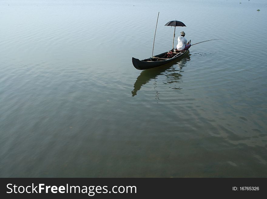 A fisherman sitting on a boat fishing in a lake