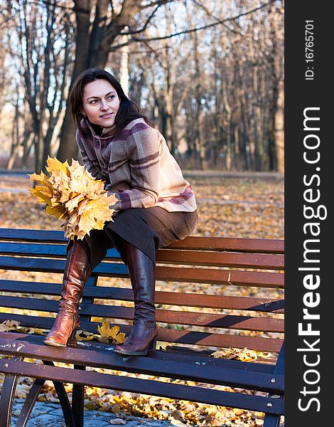 Beautiful young woman on a bench in autumn