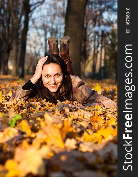 Beautiful young woman lying in autumn leaves