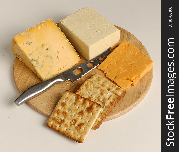 Cheese and Biscuits on a cheeseboard with a knife on a white background. Cheese and Biscuits on a cheeseboard with a knife on a white background