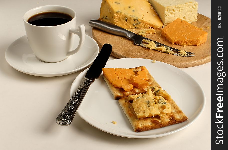 Cheese and crackers with a cup of black coffee and a cheese board with assorted cheeses. Cheese and crackers with a cup of black coffee and a cheese board with assorted cheeses