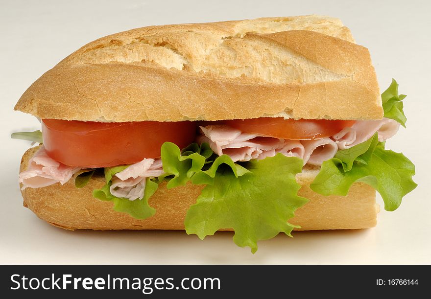 A sandwich made with fresh French Roll, ham, lettice and tomato. A sandwich made with fresh French Roll, ham, lettice and tomato
