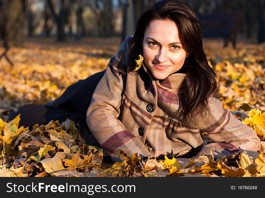 Beautiful young woman lying in autumn leaves