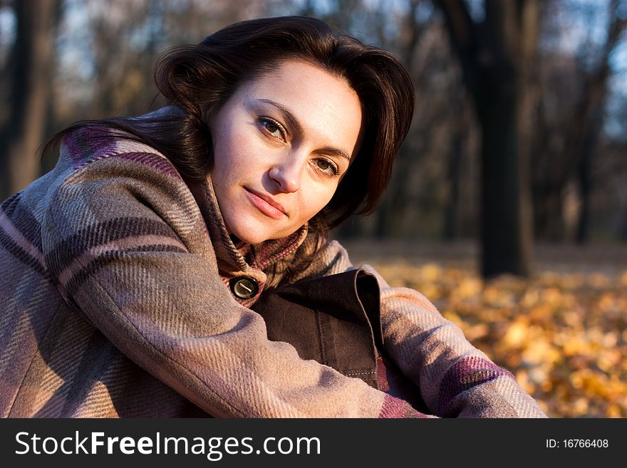 Beautiful Young Woman Sitting In Autumn Leaves