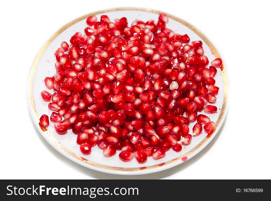 Ripe pomegranate on plate on white background