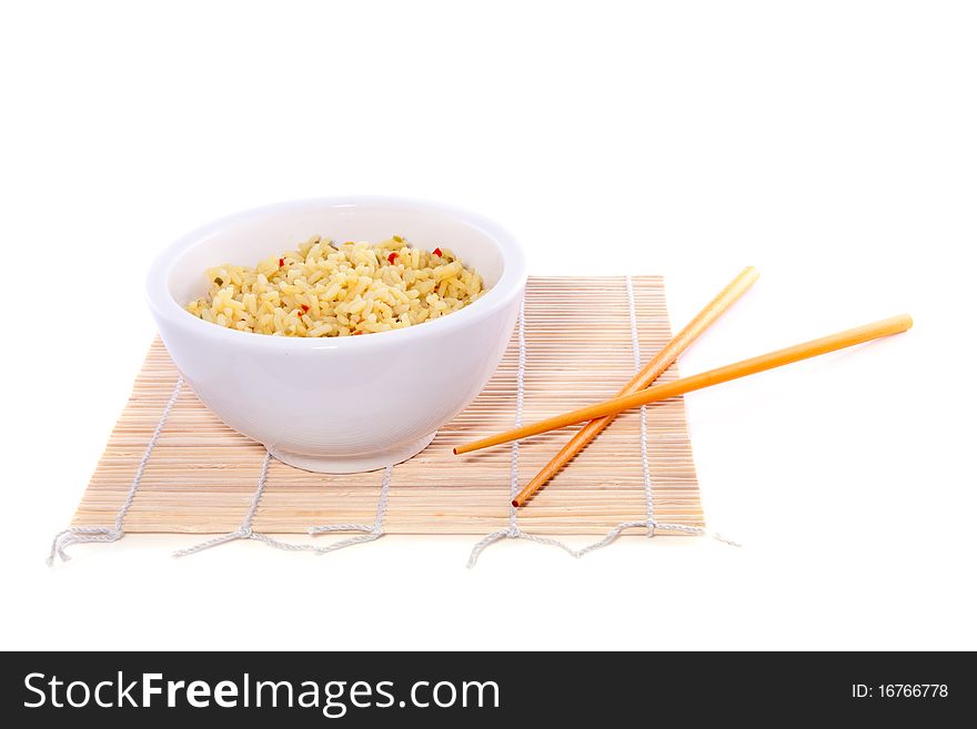 Chopsticks on top of a bowl yellow  rice  on bamboo mate isolated on white background. Chopsticks on top of a bowl yellow  rice  on bamboo mate isolated on white background