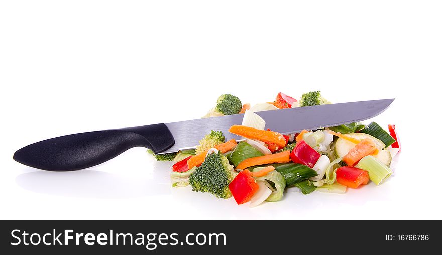 Colorful cut vegetables with a knife on top isolated over white