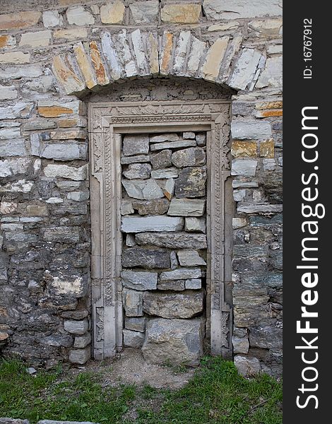 Old lithoidal wall with a doorway in form arch, heaped up by stones. Old lithoidal wall with a doorway in form arch, heaped up by stones