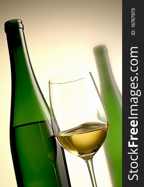Glass of white wine with green bottle in the background. Glass of white wine with green bottle in the background