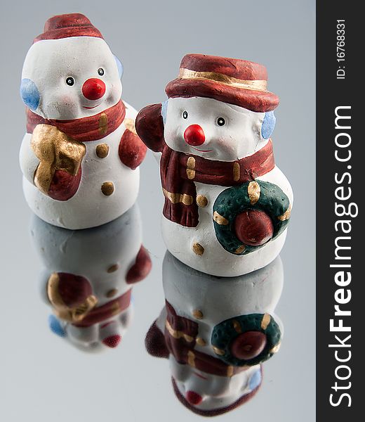 Figurines snowmen on reflex background. Figurines snowmen on reflex background