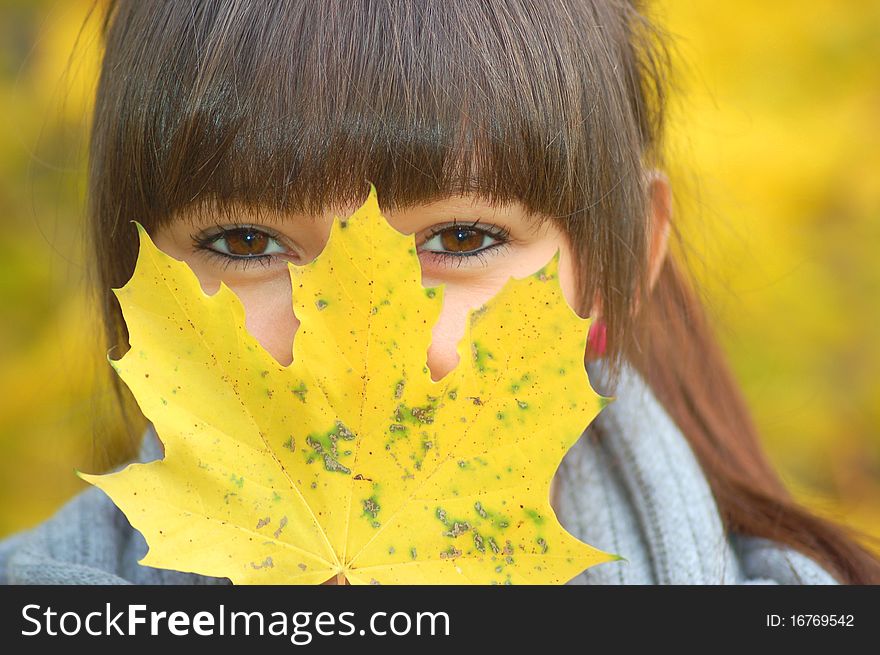 A girl hidden behind maple autumn mask. A girl hidden behind maple autumn mask