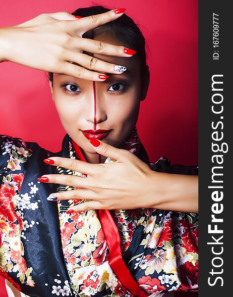 Young pretty geisha on red background posing in kimono, oriental concept closeup