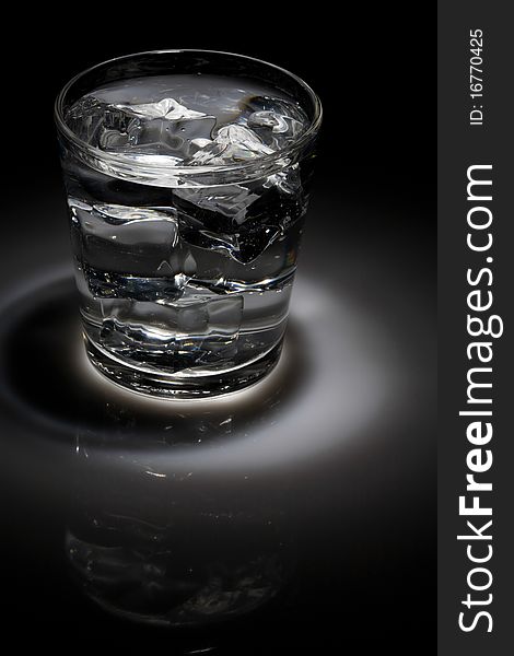 Glass of ice water in spotlight lighting. Glass of ice water in spotlight lighting.