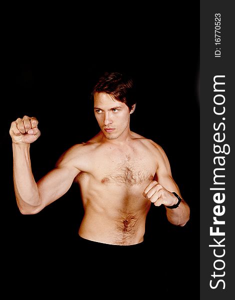 A man in a fighting stance ready to fight on a black background. A man in a fighting stance ready to fight on a black background.