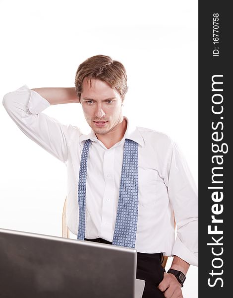 A man with his tie undone with a serious expression looking at his computer. A man with his tie undone with a serious expression looking at his computer.