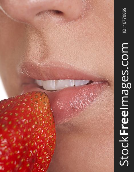 A close up of a womans lips with a red ripe strawberry. A close up of a womans lips with a red ripe strawberry.