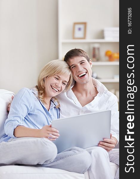 Laughing young couple with laptop at home. Laughing young couple with laptop at home