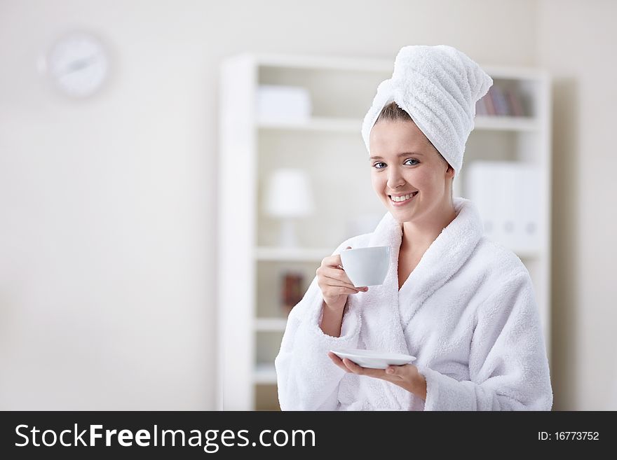 Beautiful girl in a bathrobe and a towel keeps the cup. Beautiful girl in a bathrobe and a towel keeps the cup