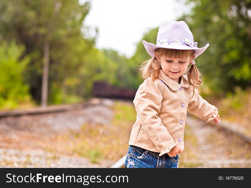 The little sweet cowgirl walks on the railway. The little sweet cowgirl walks on the railway