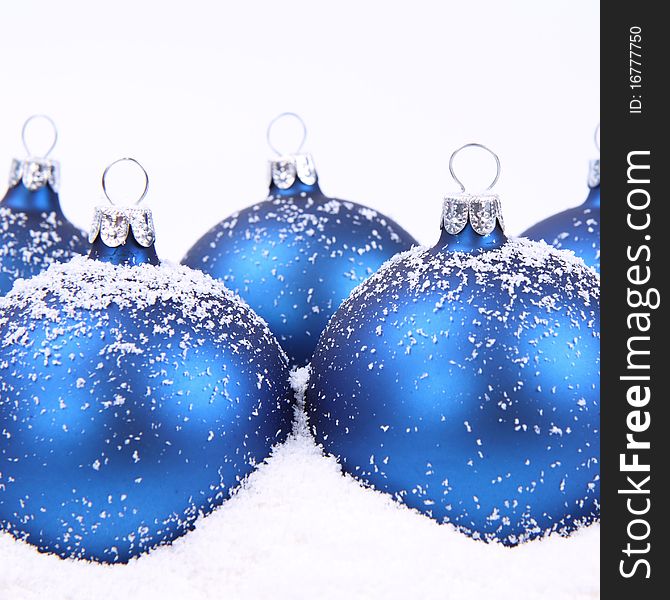 Blue matt christmas balls on snow on white background, with space for your text