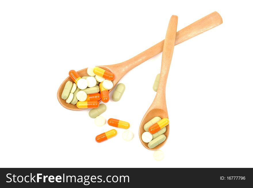 Medical pills on wooden spoons isolated on white background. Medical pills on wooden spoons isolated on white background