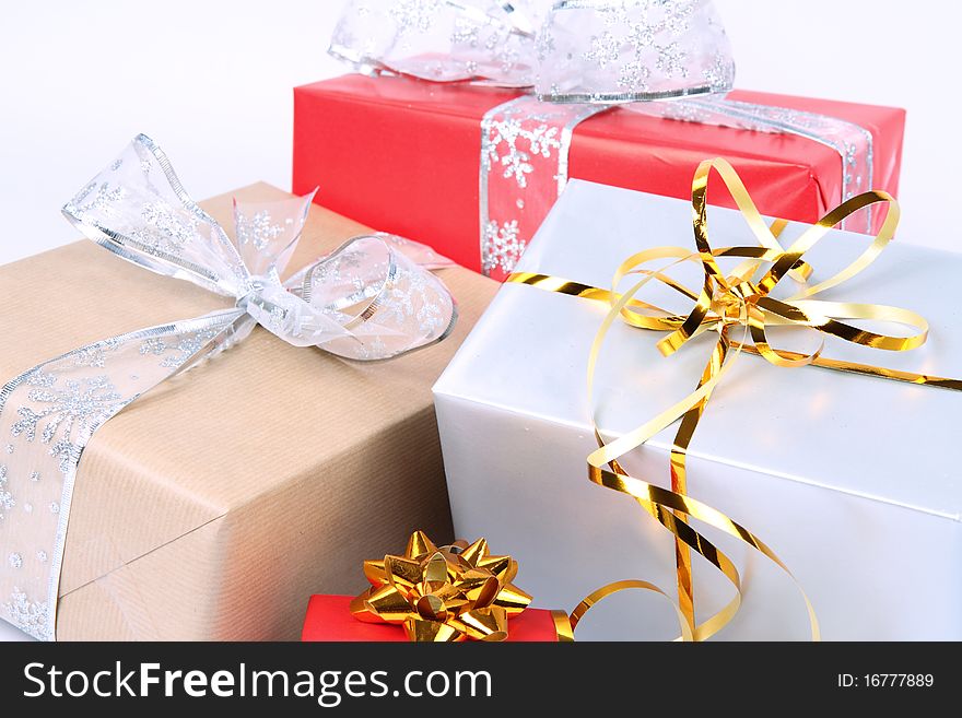 Gifts in silver, brown and red wrapping with bows on white background in close up