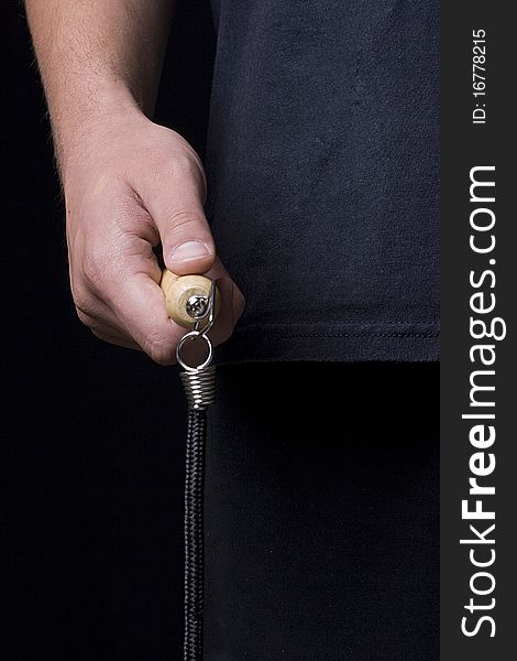 Human hand holding a jump rope on a black background.