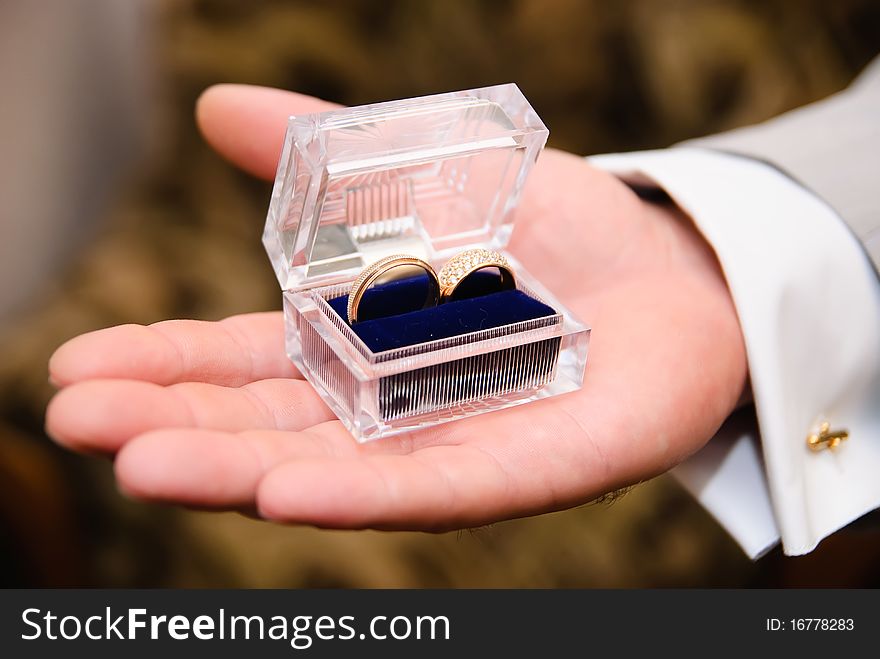 Man's hand holding a transparent box with a wedding bands