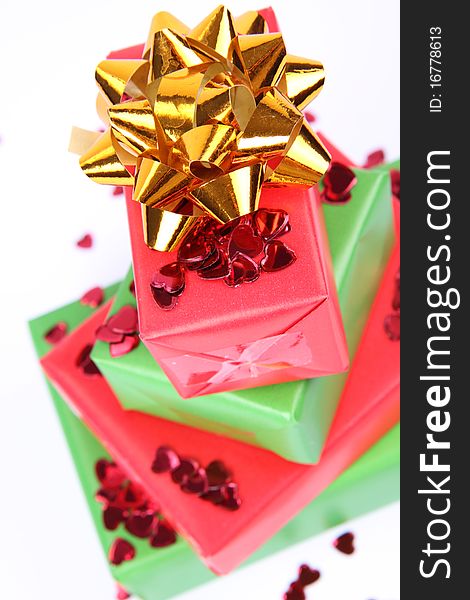 Gifts in green and red wrapping with a golden bow decorated with heart shaped confetti. Gifts in green and red wrapping with a golden bow decorated with heart shaped confetti