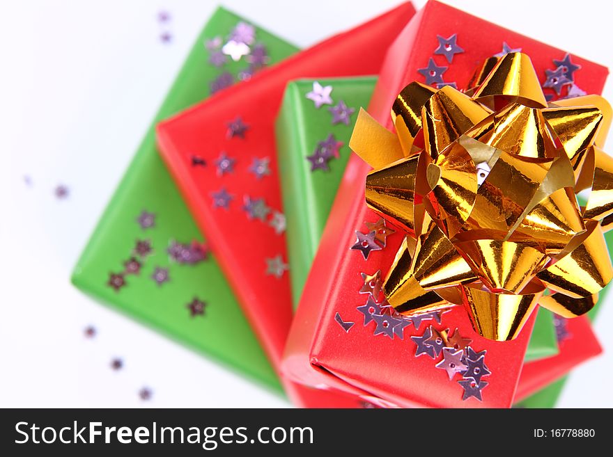 Pile of gifts in green and red wrapping with a golden bow decorated with star shaped confetti. Pile of gifts in green and red wrapping with a golden bow decorated with star shaped confetti