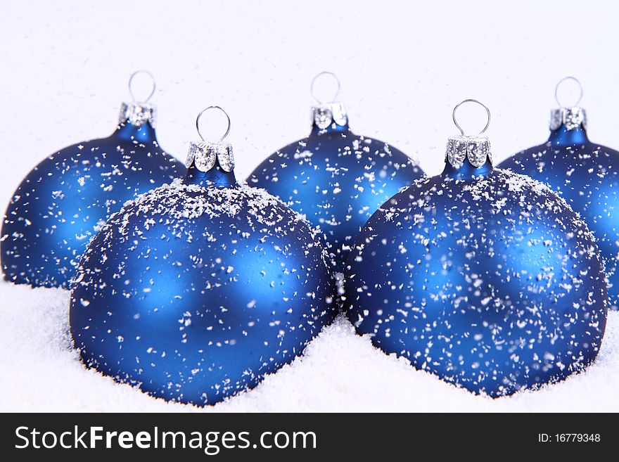 Blue matt christmas balls on snow and with snow falling on white background. Blue matt christmas balls on snow and with snow falling on white background