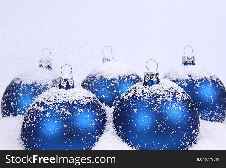 Blue matt christmas balls on snow and with snow falling on white background