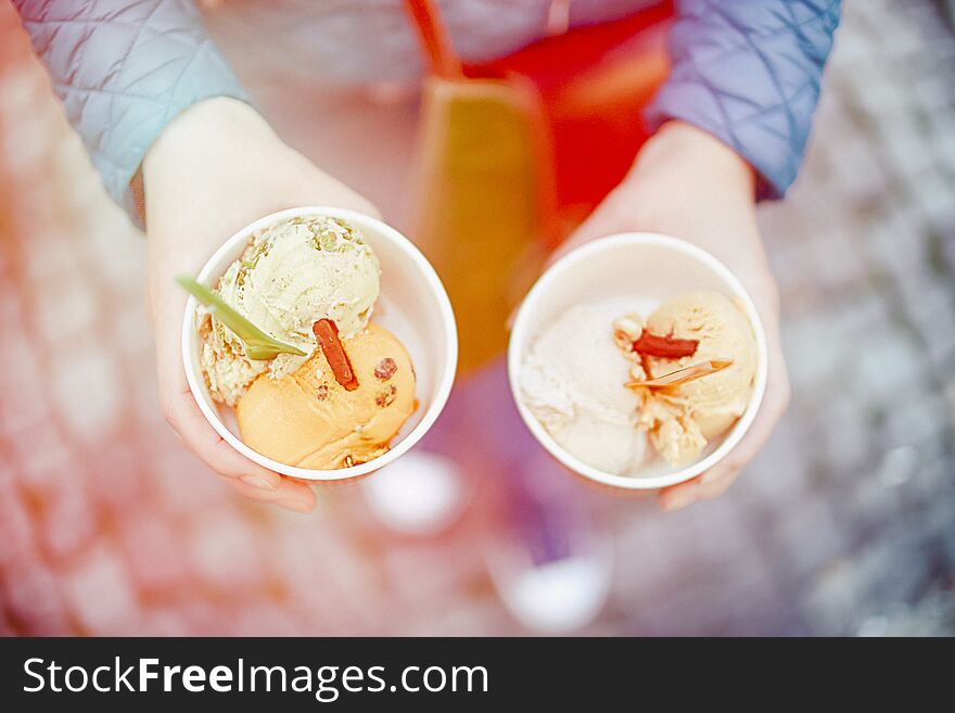 Female hands holding colored ice cream. Top view. Light toned photo